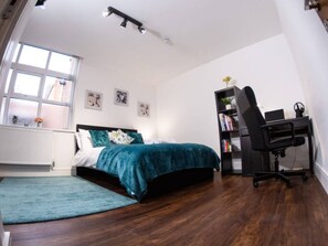A bedroom with a bed, a desk, a chair, a bookshelf, and a window. - Sav Rutland Town Centre-3 Bed Apartment (Leicester)
