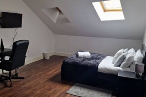 A bedroom with a bed, a desk, a chair, a TV, and a skylight. - Sav - Rutland, 4Bed in Leicester (Leicester)