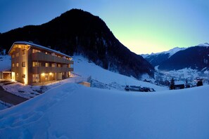 A modern building with multiple windows and balconies, surrounded by snow-covered mountains. - Chalet with fireplace and village view (Gaschurn)