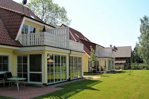 Ein Wohngebäude mit Balkon, großen Fenstern und einem gepflegten Rasen.