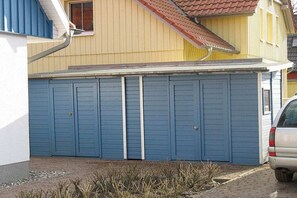 Un bâtiment à deux étages avec une porte de garage, une voiture garée devant et un petit jardin.