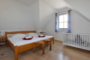 Una camera da letto con un letto di legno, una culla, una finestra con tende e un comodino.