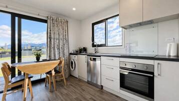 Une cuisine moderne avec un coin repas, de grandes fenêtres et une vue sur les montagnes.