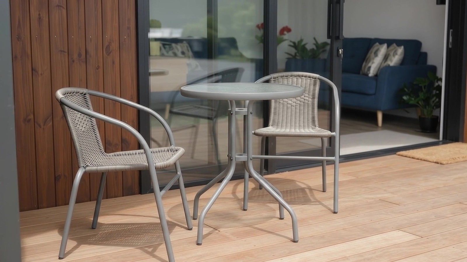 Une terrasse avec deux fauteuils en osier et une petite table ronde.