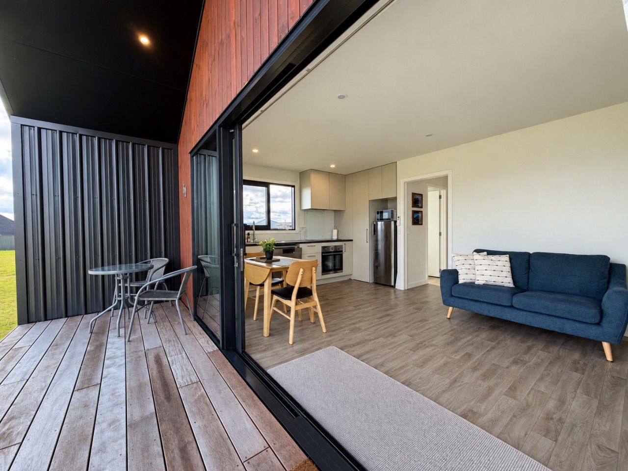 A modern interior with a dining area, a sofa, and a kitchen visible through a glass door.