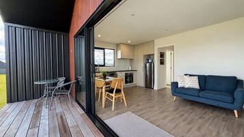 A modern interior with a dining area, a sofa, and a kitchen visible through a glass door.