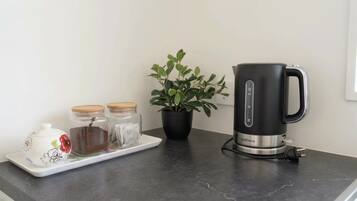 A kitchen counter with a black electric kettle, a white teapot, and two glass jars with lids.