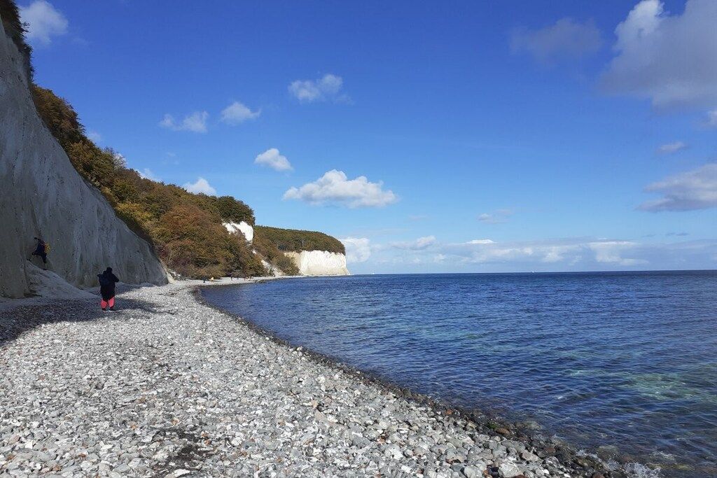 A pebbled beach with a cliff and ocean view.
