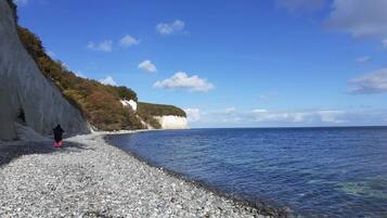 A pebbled beach with a cliff and ocean view.