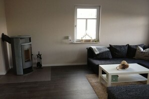 Ein Wohnzimmer mit einer Couch, einem Tisch, einem Kamin und einem Fenster.