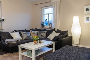 Ein Wohnzimmer mit einer Sofagarnitur, einem Couchtisch und einer Stehlampe.