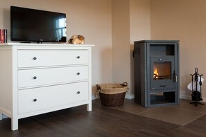 Ein Zimmer mit einem weißen Schminktisch, einem Flachbildfernseher, einem Kamin und einem Korbwäscheschrank.