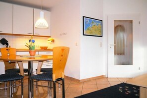 A dining area with a table, chairs, a potted plant, and a map on the wall. - Oak Park W 2.2 || Ostseebad Prerow (Ostseebad Prerow)