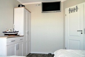 A bedroom with a bed, a wardrobe, a television mounted on the wall, and a door with a family silhouette decoration. - Holiday apartment with 2 bedrooms (Ostseebad Prerow)