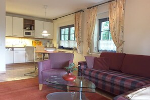 Una sala de estar con sofá, sillón y una mesa de centro de vidrio.