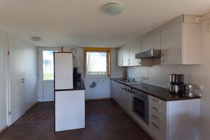 Una cocina compacta con armarios blancos, horno integrado y refrigerador.