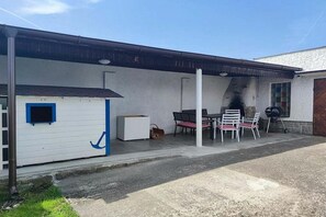 A covered outdoor area with a barbecue grill, a white shed, and a table with chairs. - Holiday home in Křemže with Wi-Fi and parking (Křemže)
