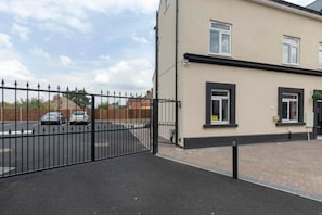 A gated parking area with a paved walkway leading to a building with a flat roof and two windows. - SAV Clarence Apt, Loughborough - 1-Bed Mandarin (Leicestershire)