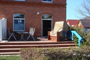 Ein Backsteinhaus mit einer Terrasse, die Gartenmöbel und eine Treppe besitzt.
