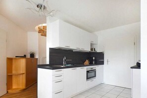 A modern kitchen with white cabinets, a black countertop, and a built-in oven. - "At the fountain" W.5 (Ostseebad Prerow)
