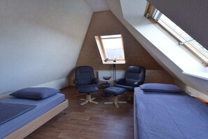 A small, triangular attic room with two beds, two chairs, a small table, and a window. - "At the fountain" W.5 (Ostseebad Prerow)
