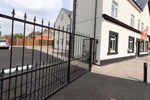 A gated entrance to a residential building with a paved driveway and a white exterior wall. - SAV Clarence Apt, Loughborough - 2-Bed The Jack (Leicestershire)