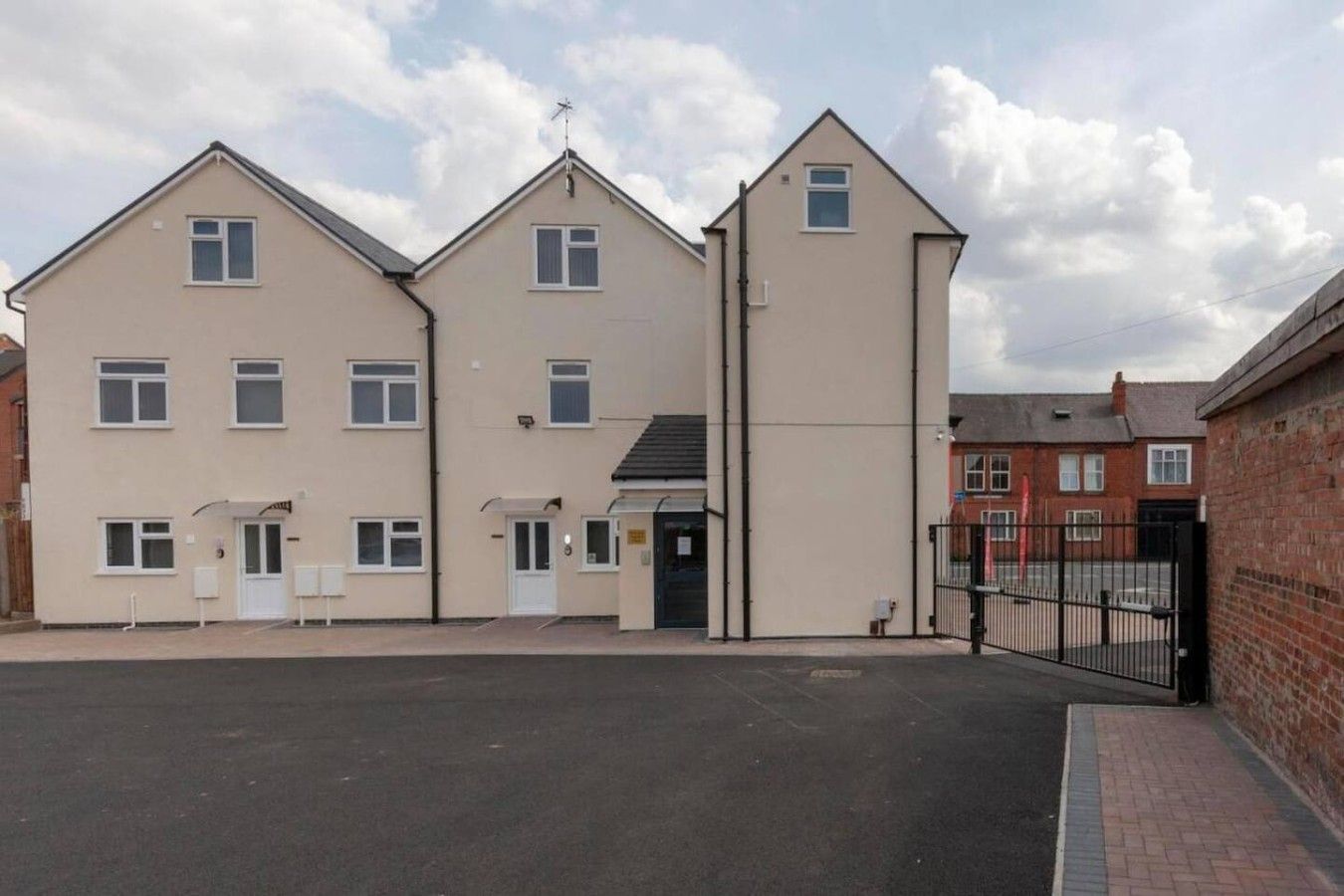 A multi-story residential building with a gated entrance and a driveway.