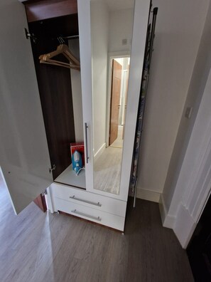 Une pièce dotée d’une armoire, d’un miroir et d’une porte donnant sur une autre pièce.