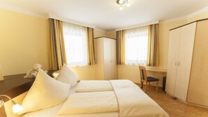 A hotel room with a bed, a desk, a chair, and a wardrobe. - Large apartment for 2 families (Kleinarl)