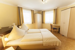 Ett hotellrum med en säng, ett skrivbord, en stol och en garderob.