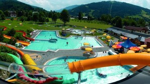 A water park with multiple slides and pools, surrounded by greenery and mountains. - Large apartment for 2 families (Kleinarl)