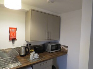 Eine Küchenzeile mit Mikrowelle, Toaster, Wasserkocher und einer Wanddecke.