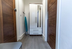 Ein schmaler Korridor mit einem Holzschrank, einer Bank und einem Spiegel.