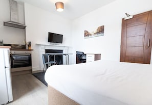 Ein Hotelzimmer mit Bett, Fernseher, Kamin, Schreibtisch und Kleiderschrank.