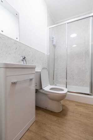 A bathroom with a toilet, a shower enclosure, and a cabinet. - Sav Regent Leicester-Studio Walking to City Centre (Leicester)