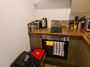 Een kleine keuken met een broodrooster, waterkoker en een magnetron op het aanrecht.