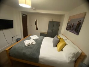 A hotel room with a bed, bedside table, lamp, wardrobe, and a painting on the wall. - Sav | Regent | Leicester-Studio Walking to Demont (Leicester)