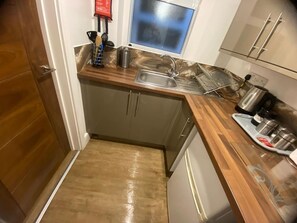 A compact kitchen with a wooden countertop, stainless steel sink, and a small window above the sink. - Sav | Regent | Leicester-Studio Walking to Demont (Leicester)