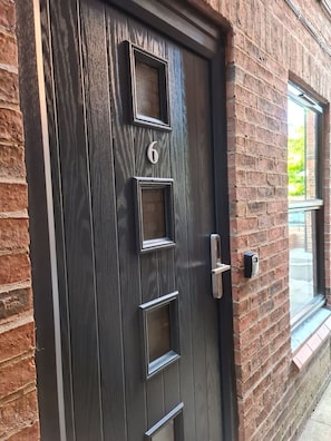 Une porte en bois sombre, dotée d’un clavier numérique et d’une poignée de porte moderne.