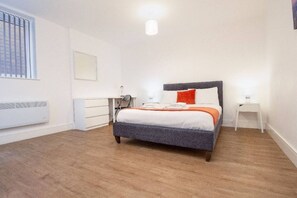 Ein Schlafzimmer mit Bett, Schreibtisch, Stuhl, Heizung und Fenster.