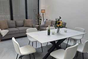 Ein modernes Wohnzimmer mit einem grauen Sofa, einem weißen Tisch und einer Vase mit Sonnenblumen.