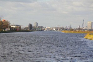 En flod med bygninger og byggekraner i baggrunden.