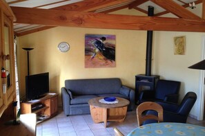 A cozy living room with a sofa, a television, a round wooden table, and a painting on the wall. - Zeebos Holiday Park 24 (Bredene)