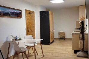 Eine moderne Küche mit einer Tafel, Holzschränken und einer Essecke mit weißen Stühlen.