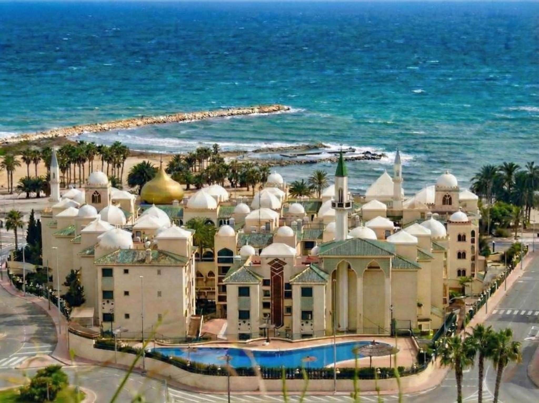 Ein Küstenhotel mit mehreren Kuppelbauten, einem Schwimmbecken und Meerblick.