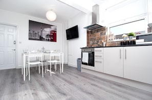 A modern kitchen with white cabinetry, a black countertop, and a tiled backsplash. - 4 Bed House Harrow Near Wembley (Harrow)
