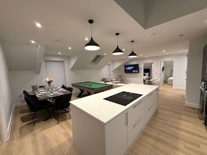 A modern kitchen with a central island, dining area with a pool table, and a living space with a TV. - 3 Bed Penthouse Near Airport & Trafford Centre (Wythenshawe)