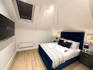 A bedroom with a bed, bedside tables, a TV, and a window. - 3 Bed Penthouse Near Airport & Trafford Centre (Wythenshawe)