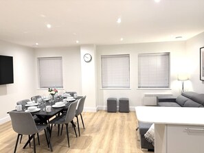 A modern living room with a dining area, a sofa, and a TV mounted on the wall. - 2 Bed+Sofa in Sale Near Airport & Trafford Centre (Wythenshawe)