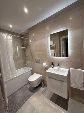 A modern bathroom with a glass-enclosed shower, a toilet, a sink with a mirror, and a towel rack. - 1 Bed+Sofa in Sale Near Airport & Trafford Centre (Wythenshawe)